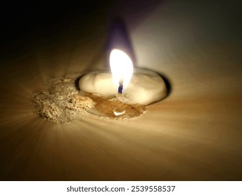 Photo of the flame of a small candle that has begun to dim because it has been burned on a tombstone on the occasion of World Spirits Day - Powered by Shutterstock