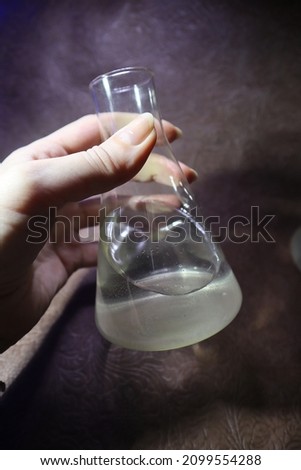 Photo of a flask with acid held by a girl. Flask with nitric, phosphoric, sulfuric acid, hydrochloric acid
