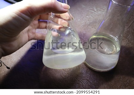 Photo of a flask with acid held by a girl. Flask with nitric, phosphoric, sulfuric acid, hydrochloric acid