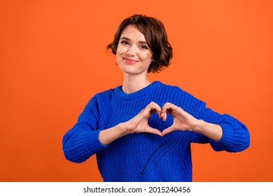 Photo of flirty brunette millennial lady show heart wear blue pullover isolated on orange color background