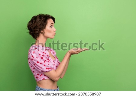 Photo of flirty sweet girl dressed print top sending arms kiss empty space isolated green color background