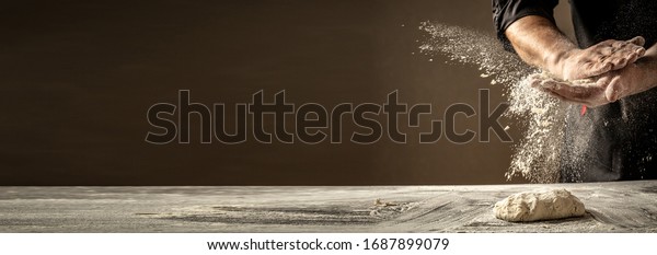 Foto von Mehl und Männern Hände mit Mehl splash. Brot kochen. Den Teig kneten. Einzeln auf dunklem Hintergrund. Leerer Platz für Text.