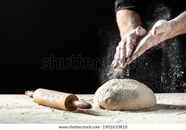 Photo of flour and men hands with flour splash.\
Cooking bread. Kneading the Dough. Isolated on dark background.\
Empty space for text.