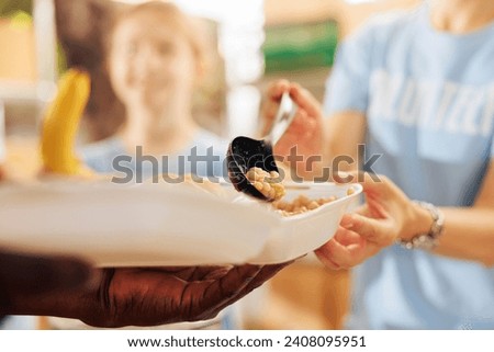 Photo focus on caucasian woman serving baked beans to hungry underprivileged african american person at a non-profit food drive. Close-up shot of free food distribution by humanitarian aid team.
