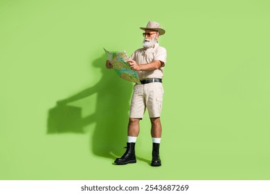 Photo of focused old senior man reading map for finding trip destination wear safari suit hat boots isolated green color background - Powered by Shutterstock