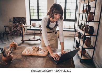 Photo of focused self-employed lady potter inspired shaping crockery search netbook webinar in workroom - Powered by Shutterstock