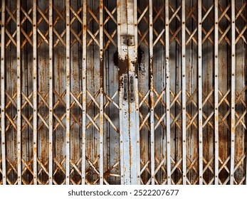 Photo of a folding metal door made of iron. The iron door is in an old, closed condition with a lot of rust on the iron. There is a handle for opening and closing the door in the middle of the photo. - Powered by Shutterstock