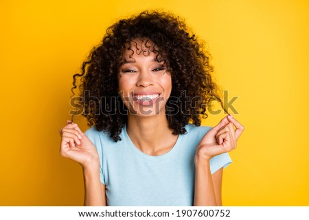 Photo of fooling sweet dark skin wavy lady wear blue t-shirt hands arms holding curls isolated yellow color background