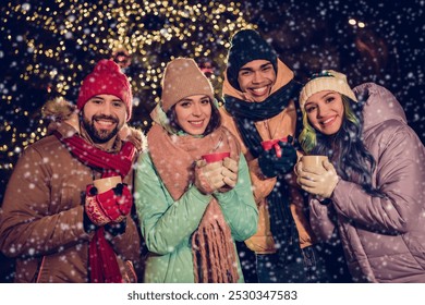 Photo of four cheerful fellows hands hold hot chocolate tea mug enjoy magic spirit city center lights outside - Powered by Shutterstock