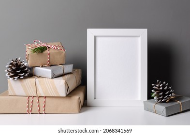 Photo Frame Mockup With Decorated Christmas Gift Boxes And Cones Over Grey Wall