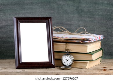 Photo Frame And Pile Of Old Books On Wooden Table