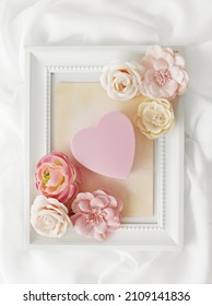 photo frame, pink heart and little flowers on white silk background. Valentine's Day or wedding - Shutterstock ID 2109141836