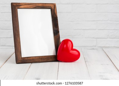 Photo frame and red heart on white wood table with copy sapce, love concept.