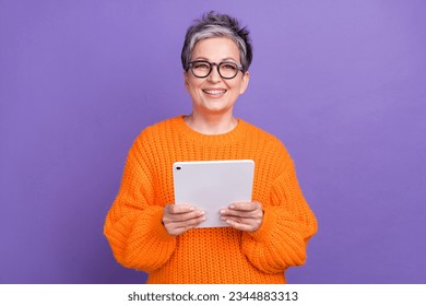 Photo of friendly business lady pensioner holding her moder samsung galaxy tablet browsing internet isolated on violet color background - Powered by Shutterstock