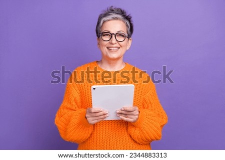Photo of friendly business lady pensioner holding her moder samsung galaxy tablet browsing internet isolated on violet color background
