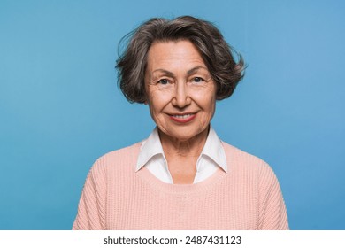 Photo of friendly mature elderly woman granny grandmother in pastel pink sweater casual clothes smiling looking at the camera isolated over blue background. Advertisement concept - Powered by Shutterstock