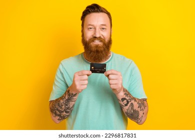 Photo of friendly nice person toothy smile arms hold showing plastic debit card isolated on yellow color background - Shutterstock ID 2296817831