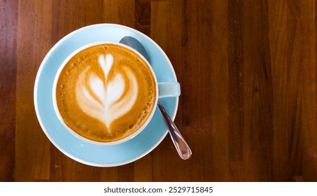 Photo of a frothy cappuccino in a cup, resting on a wooden table. Perfect for conveying cozy café atmospheres, coffee culture, or lifestyle themes, for use in food blogs or coffee shop promotions - Powered by Shutterstock