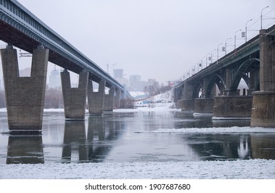 Photo of the frozen Ob River with road and subway bridges on a winter snowy day. Novosibirsk, Siberia, Russia.