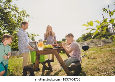 Photo Of Full Big Family Gathering Five People Three Small Kids Dad Hold Ice Bag Child Have Fun Served Breakfast Table Barbecue Sunny Summer Day Green House Garden Backyard Outside