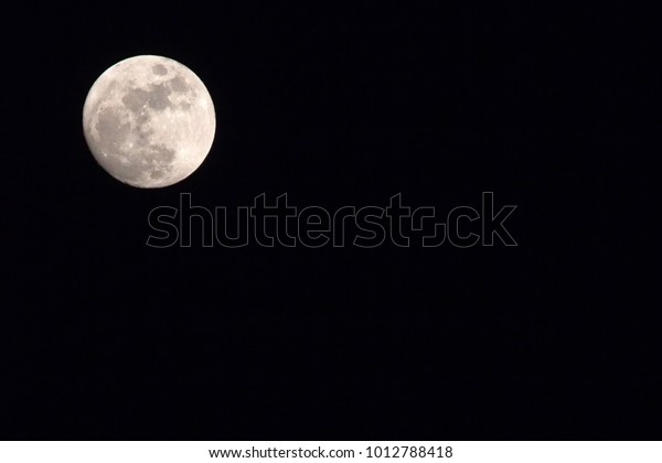 Photo\
of a full moon in the corner of a dark night sky.\

