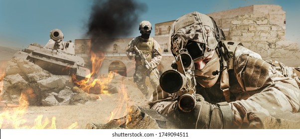 Photo of a fully equipped soldiers laying and aiming rifle on desert battlefield with running soldiers and tank.