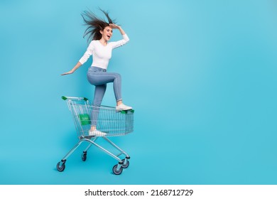 Photo of funky adorable woman wear white shirt riding shopping tray looking far away empty space isolated blue color background - Shutterstock ID 2168712729