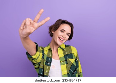 Photo of funky cheerful person beaming smile arm fingers demonstrate v-sign number two isolated on violet color background