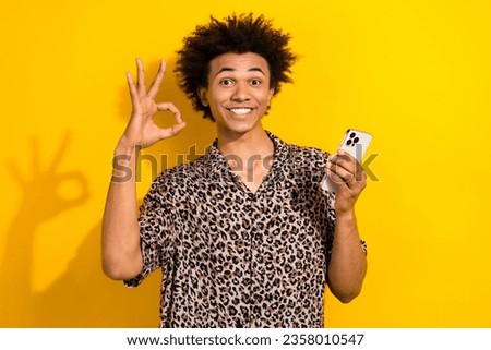 Photo of funky confident guy dressed leopard print shirt showing okey typing apple samsung iphone device isolated yellow color background