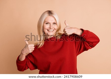 Photo of funky confident woman wear red sweater showing two thumbs up isolated beige color background
