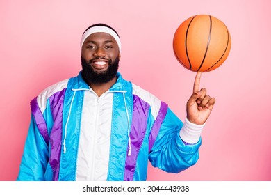 Photo of funky cool dark skin man wear blue suit headband spinning finger basketball ball smiling isolated pink color background
