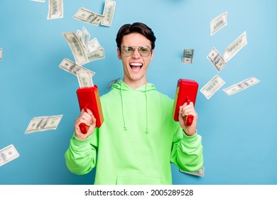 Photo Of Funky Cool Young Guy Dressed Green Hoodie Shooting Money Gun Smiling Isolated Blue Color Background