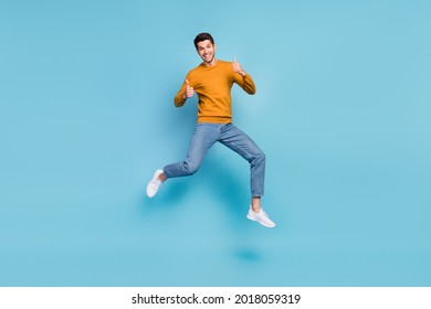 Photo of funky cute young man wear yellow sweater smiling jumping high showing thumbs up isolated blue color background - Shutterstock ID 2018059319