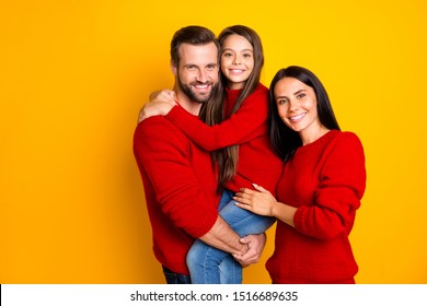 Photo Of Funky Day Toothy Nice Fascinating Family With Kid Wearing Jeans Denim Red Sweater Father Holding Daughter With Hands Mother Embracing Isolated Over Vivid Color Background