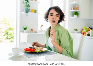 Photo of funky dreamy lady dressed green shirt enjoying tasty meal closed eyes indoors house kitchen