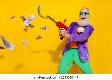 Photo of funky eccentric granddad hold money guns luxury life wealth wear bright costume empty space isolated on yellow color background