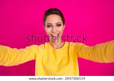 Photo of funky fooling young woman dressed yellow pullover showing tongue recording video smiling isolated pink color background