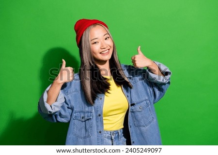 Photo of funky good mood girl dressed jeans shirt showing two thumbs up empty space isolated green color background