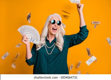 Photo Of Funky Grandma Lady Hold Fan Usa Bucks Money Fall From Sky Wealthy Rich Person Freelance Job Income Wear Green Shirt Sun Specs Necklace Isolated Bright Yellow Color Background