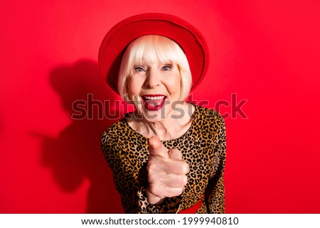 Photo of funky happy cheerful old woman point finger you teasing wear hat leopard dress isolated on red color background