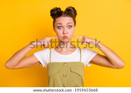 Photo of funky lady inflate cheeks press fingers look camera wear green overall isolated yellow background