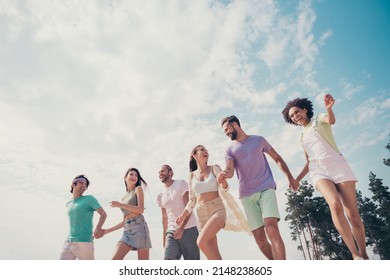 Photo of funky pretty young six friends wear casual clothes smiling holding arms walking laughing outside countryside