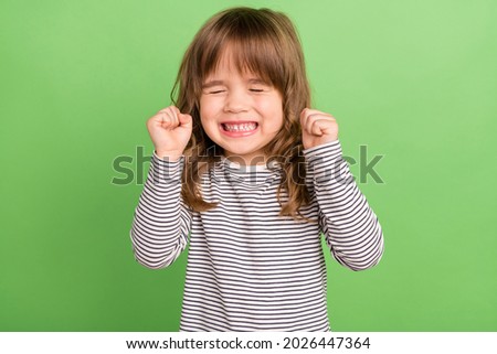 Photo of funky small blond hair girl hands fists wear striped shirt isolated on green color backgound