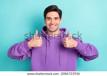 Photo of funky street style wear guy in violet hoodie showing thumb-up recommend isolated on blue color background