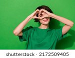 Photo of funny adorable young lady dressed casual t-shirt smiling showing fingers heart isolated green color background