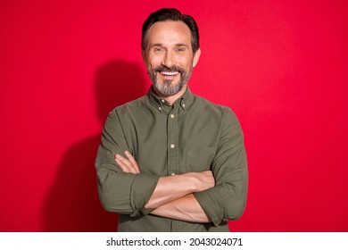 Photo of funny age brunet man crossed arms wear khaki shirt isolated on red color background