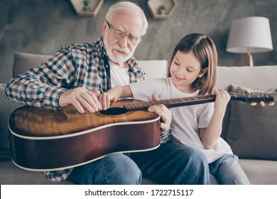 Photo of funny aged old grandpa little pretty granddaughter holding playing guitar teaching small princess bonding spend stay home quarantine useful time modern interior living room indoors