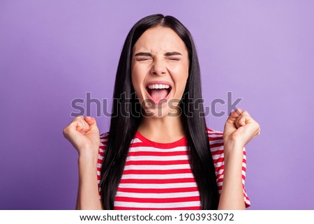 Photo of funny astonished lady open mouth raise fists eyes closed wear striped red shirt isolated purple color background