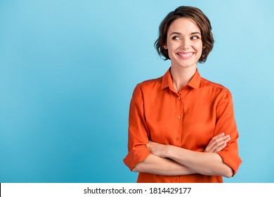 Photo Of Funny Attractive Cheerful Lady Bobbed Hairdo Arms Crossed Self-confident Person Worker Good Mood Look Side Empty Space Sly Eyes Wear Orange Office Shirt Isolated Blue Color Background