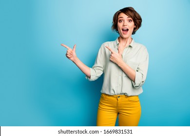 Photo of funny attractive lady indicating fingers empty space advising cool low prices shopping open mouth wear casual green shirt yellow trousers isolated blue color background